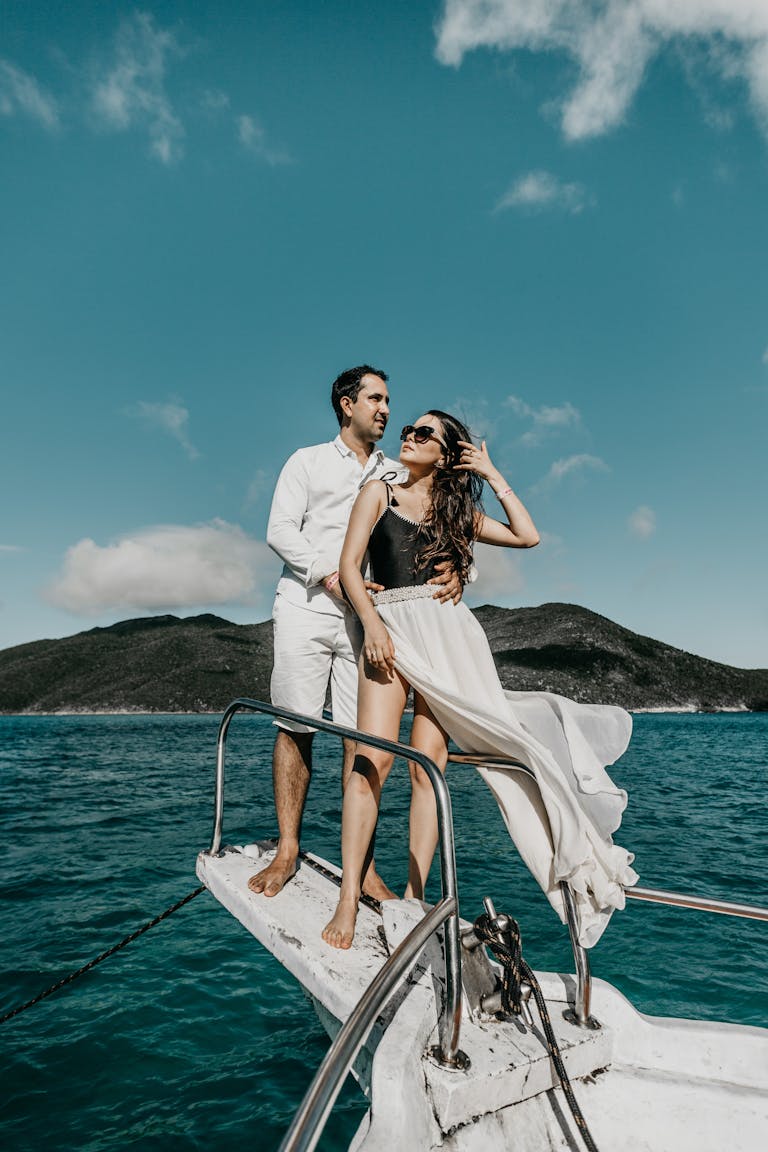 Couple standing close on bow of yacht